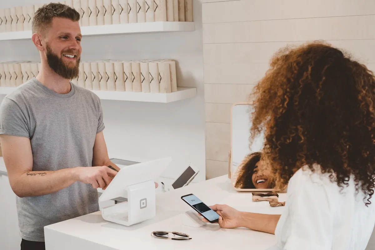 Commerçant souriant avec une cliente satisfaite illustrant l'impact des avis Google